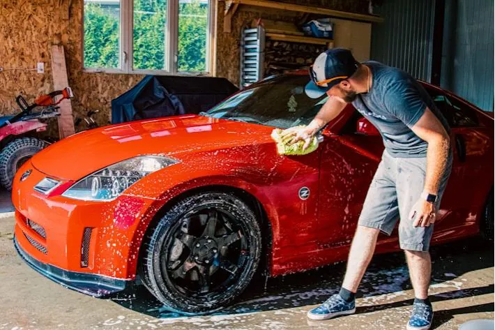 Man hand-washing a red sports car