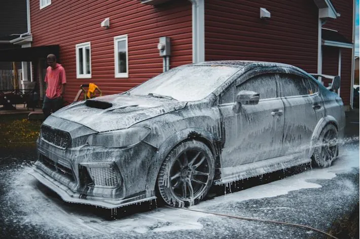 Foam-covered Subaru in front of a red barn