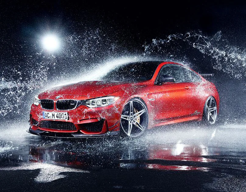 Red BMW coupe driving through a burst of water spray