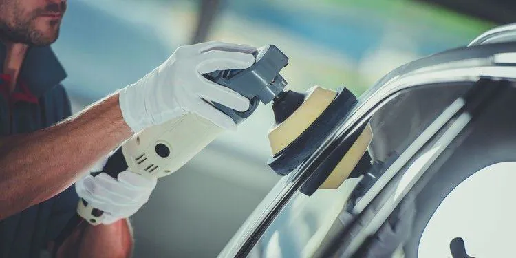 Polishing machine restoring the paint of a dark car